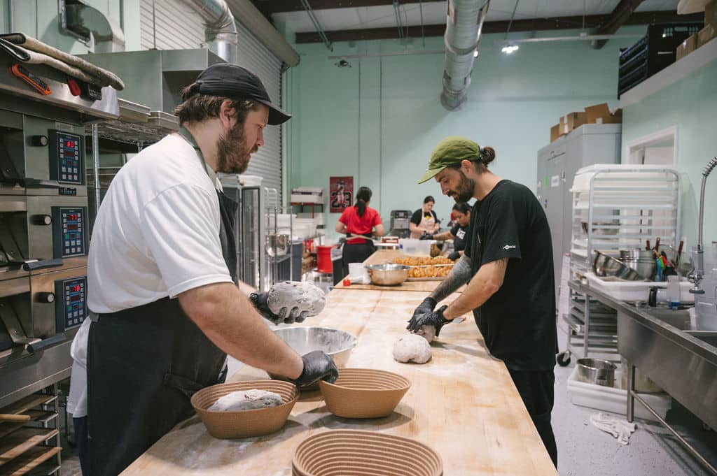 Bakers preparing sourdough bread in a commercial kitchen.