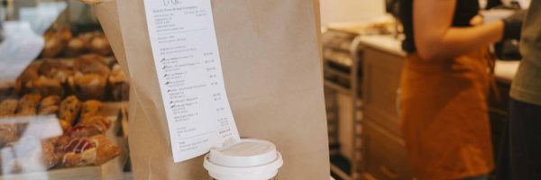 Dutch Oven bakery bag with receipt, coffee cup, and fresh pastries on the counter.