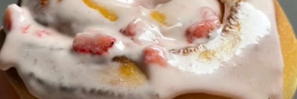 Strawberry sweet roll with pink icing and diced strawberries, fresh baked sourdough dessert.